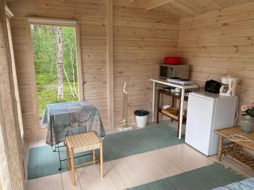 a kitchen with a refrigerator and a table in a cabin at Lemmenjoen Lumo - Nature Experience & Accommodation in Lemmenjoki