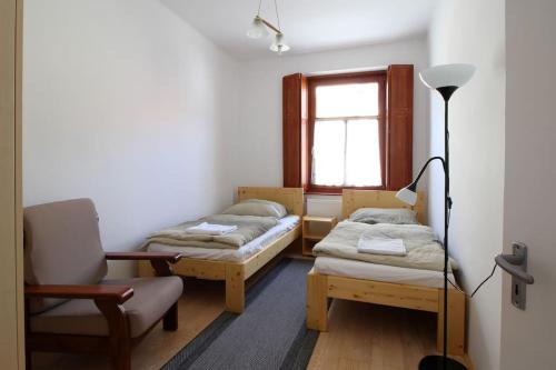 um quarto com duas camas e uma cadeira e uma janela em Körtefa Vendégház Keszthely em Keszthely