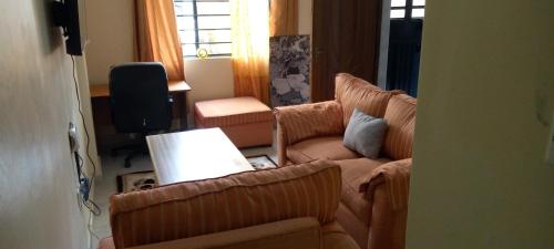 ein Wohnzimmer mit einem Sofa und 2 Stühlen in der Unterkunft TRANGQUIL APARTMENTS in Kitengela 