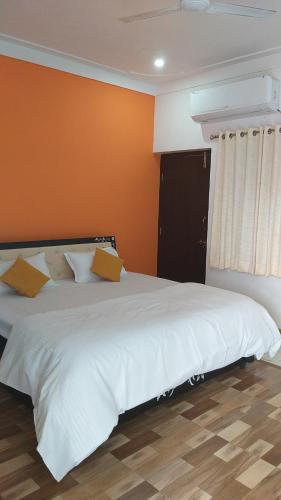 a bedroom with a white bed with an orange wall at City and Palace view guest House in Udaipur