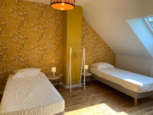 Duas camas num quarto com uma parede amarela em COTTAGE DU PARC em Albert