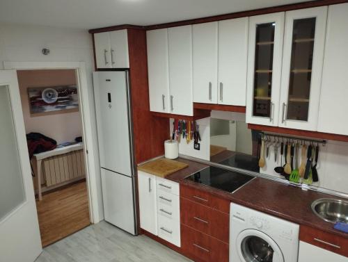 a kitchen with white cabinets and a washer at 3 hab 2 baños parking terraza in Soria