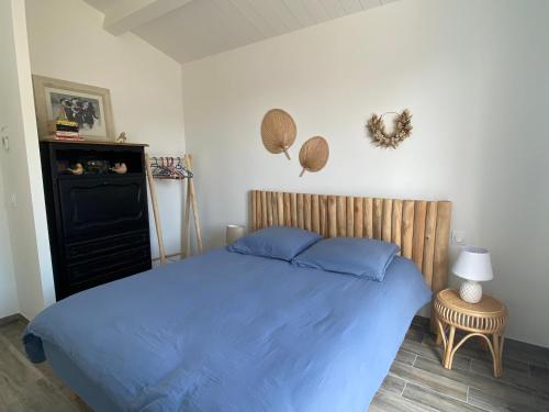 a bedroom with a blue bed with a wooden headboard at HOOliRé17 3étoiles in Ars-en-Ré
