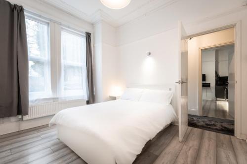南安普敦的住宿－Newly Renovated 2 Bed Ground Floor Flat，白色的卧室设有一张白色大床和一个窗户。