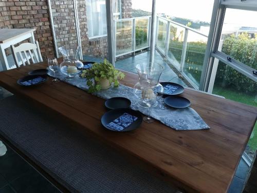 a wooden table with glasses and plates on it at BellaBlues in Herolds Bay