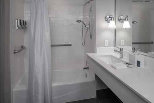 a white bathroom with a shower and a sink at Four Points by Sheraton Orlando International Drive in Orlando