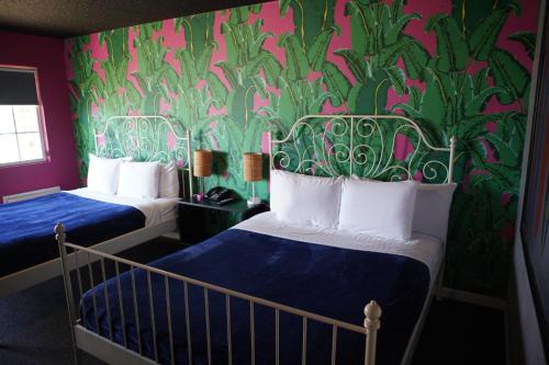 a bedroom with two beds and a green and pink wall at Huntington Surf Inn in Huntington Beach