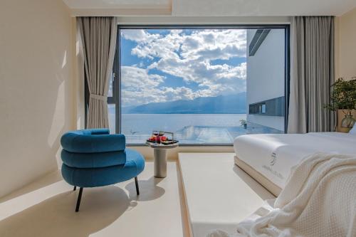 a bedroom with a blue chair and a large window at Dali Oriental Seaview Hotel -Dali Erhai in Dali