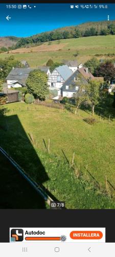 une photo d'un champ avec des maisons en arrière-plan dans l'établissement Sehr schön und gemütlich Ferienwohnung, à Netphen