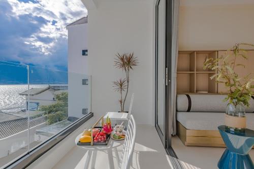 a room with a balcony with a bed and a table with fruit at Dali Oriental Seaview Hotel -Dali Erhai in Dali