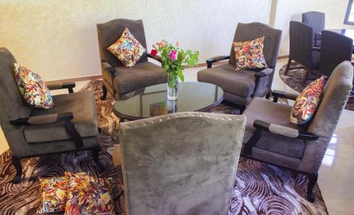 a room with chairs and a table with a vase of flowers at Hôtel La Chambotte in Imouzzer du Kandar
