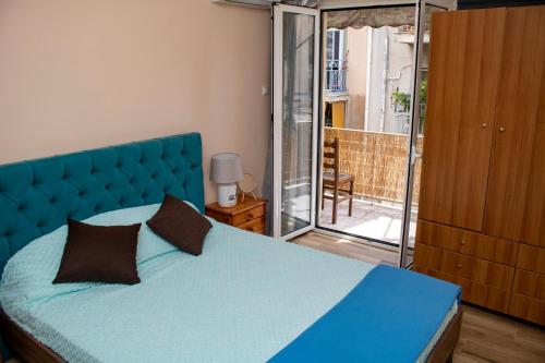 um quarto com uma cama azul e uma varanda em Acropolis rooftop view, 200m from Neos kosmos metro station em Atenas