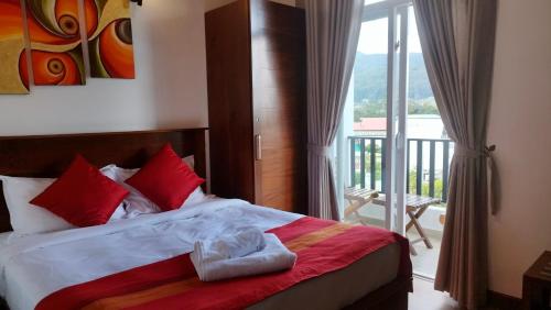 a bedroom with a bed with red pillows and a balcony at Skylight Apartment in Nuwara Eliya