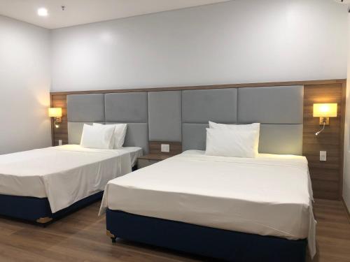 Central Halong Hotel في ها لونغ: سريرين في غرفة الفندق مع شراشف ووسائد بيضاء
