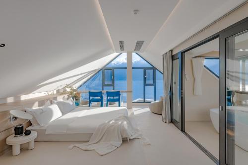 a bedroom with a white bed and a large window at Dali Oriental Seaview Hotel -Dali Erhai in Dali