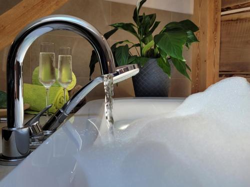 - un lavabo avec de l'eau provenant d'un robinet et 2 verres à vin dans l'établissement Landhotel Großeiberhof, à Waldmünchen