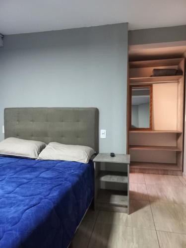 a bedroom with a blue bed and a table at Aquariu's Pousada e Restaurante in Cêrro Negro