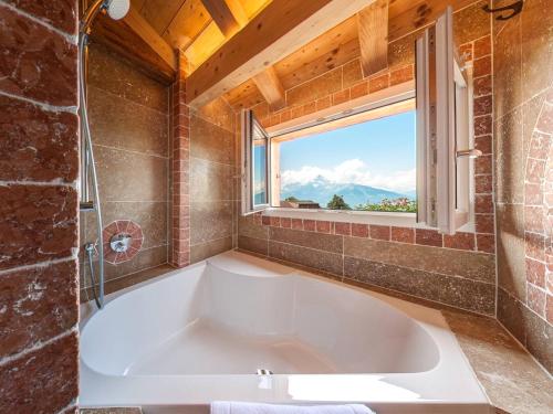 a large bath tub in a bathroom with a window at Alpe Fleurie Hôtel & Restaurant in Villars-sur-Ollon