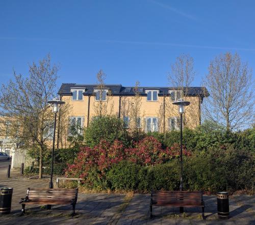 two benches in a park in front of a building at Light modern 1 bedroom apartment in Cambridge