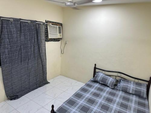 1 dormitorio con 1 cama con cortina y ventana en Room available in one bedroom appartment dating not allowd thare en Sharjah