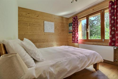 ein Schlafzimmer mit einem Bett und einer Holzwand in der Unterkunft Cable Car 1min Walk, Fully Renovated In 2017 in Champéry