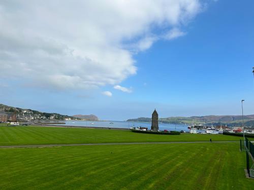 a green field with a lighthouse and a body of water at Camisila in Campbeltown
