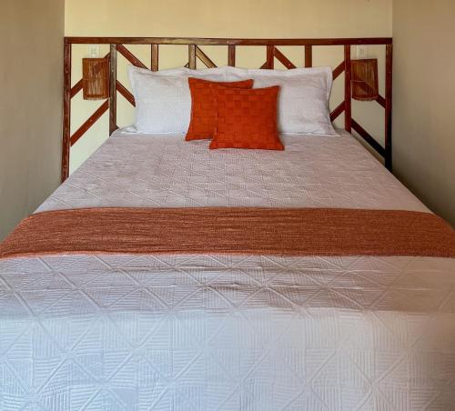 a large bed with an orange pillow on it at Kadoshi Pipa Boutique Hospedagem in Pipa