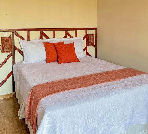 a bedroom with a large bed with orange and white pillows at Kadoshi Pipa Boutique Hospedagem in Pipa