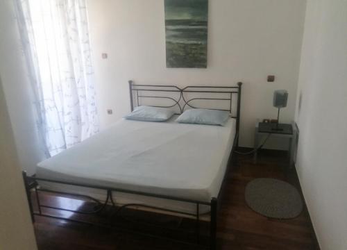 een slaapkamer met een bed met witte lakens en een raam bij 6 pax Glyfada 2floor apartment in Athene