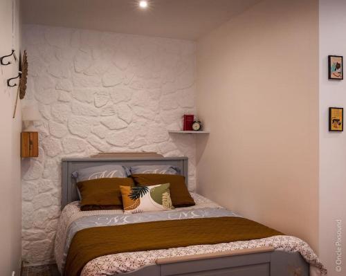 uma cama num quarto com uma parede branca em Studio Le chat’Oh! em Combourg
