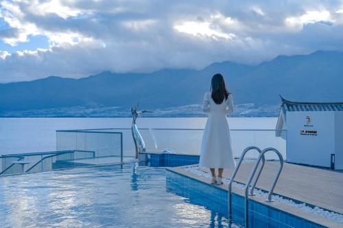 a woman in a white dress standing next to a swimming pool at Dali Oriental Seaview Hotel -Dali Erhai in Dali
