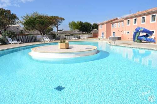 a large swimming pool with blue water in a building at Le Mas aux Amoureux , Suite Romantique et Spa in Le Barcarès
