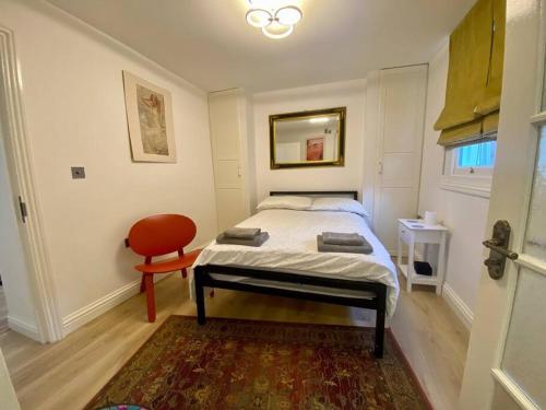 a bedroom with a bed and a red chair at Cosy Studio in trendy Islington, w/private garden! in London