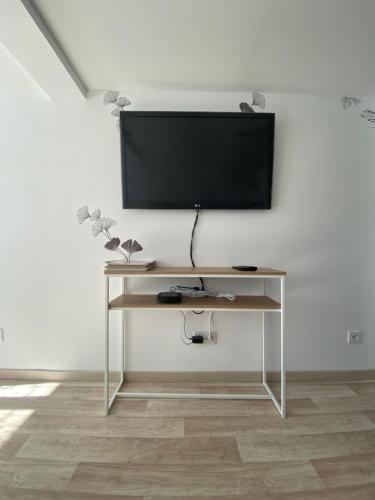 uma televisão de ecrã plano numa parede branca com uma secretária em La Foulnerie Studio avec cour autonome 61270 Rai proche 61300 l'Aigle 