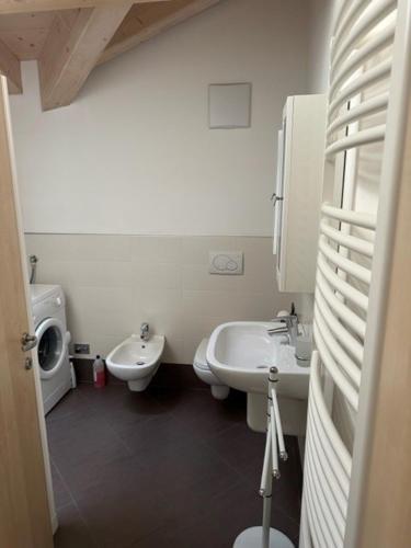 a white bathroom with two sinks and a toilet at Mansarda Cimbra in Folgaria
