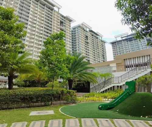 a green slide in a park with tall buildings at VERDON PARC CONDOMINIUM in Davao City