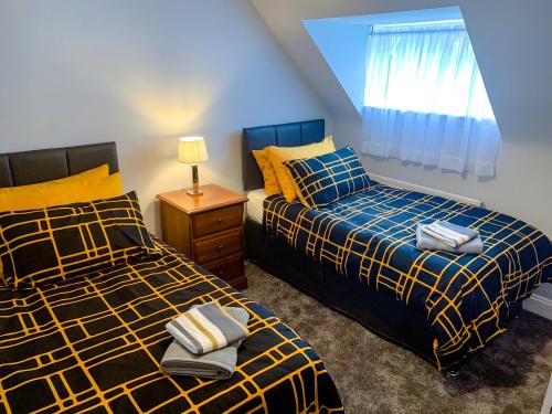 a bedroom with two beds and a window at The Gables Poole, 3 Bedroom Penthouse Apartment in Poole