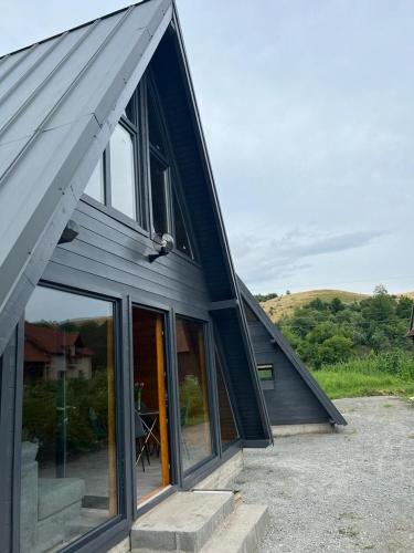 a house with large glass windows and a roof at Little House Bologa in Bologa