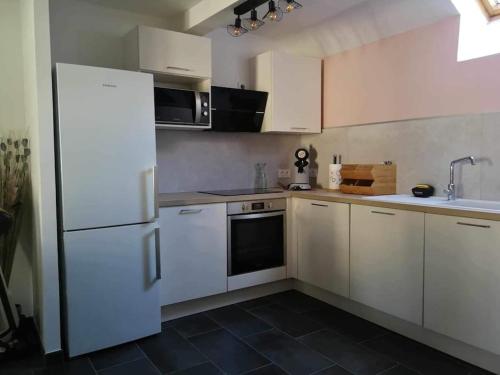 cocina con armarios blancos y suelo de baldosa negra en appartement duplex en Beaune-la-Rolande