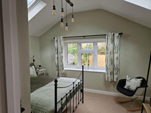 a bedroom with a bed and a window and a chair at Idyllic period cottage, Ramsbury, Nr Marlborough in Ramsbury