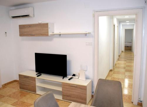 uma sala de estar com uma televisão e uma secretária com cadeiras em Apartamentos Atlas Terrassa II em Terrassa