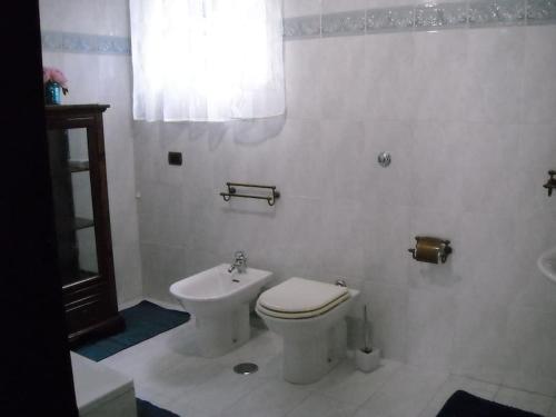 a white bathroom with a toilet and a sink at Chez moi in Colleverde