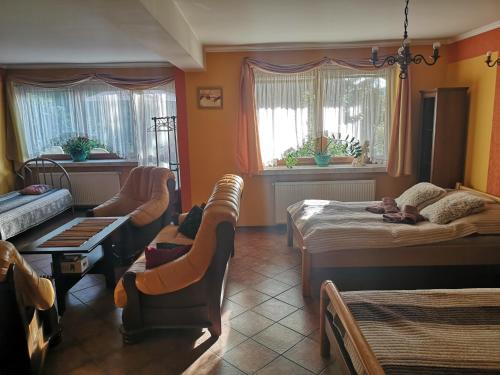 a bedroom with two beds and a chair and a couch at Apartament Fort Owcza Góra in Kłodzko