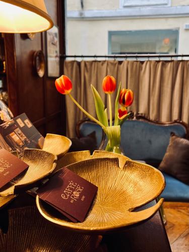 a table with a vase of red tulips on it at Caffè delle Rose Les Chambres in Verbania