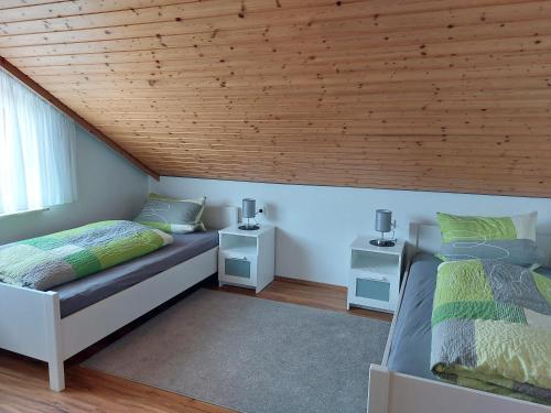 two beds in a bedroom with a wooden ceiling at Moderne Ferienwohnung - neu renoviert - ruhige Lage in Waldachtal