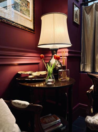 a table with a lamp and flowers on it at Caffè delle Rose Les Chambres in Verbania