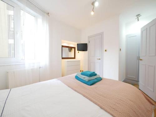 Un dormitorio blanco con una cama con una toalla azul. en Chelsea Cloisters en Londres