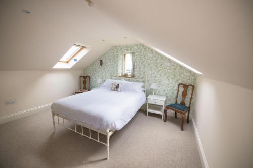 een slaapkamer met een bed en een stoel op zolder bij Winsbury Cottage in West Hauxwell