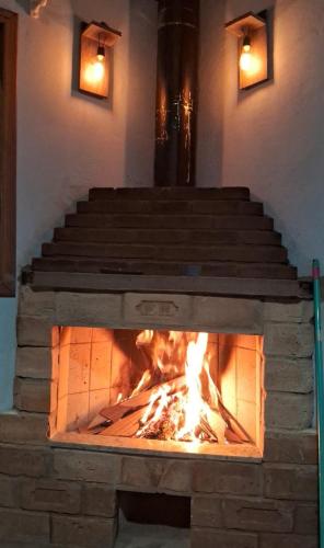 a brick fireplace with a fire in it at Chalé dois irmãos in Visconde De Maua