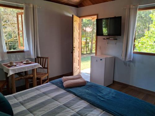 um quarto com uma cama, uma televisão e uma mesa em Chalé dois irmãos em Viscode de Mauá